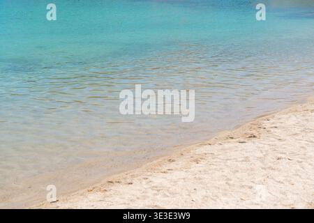 Clean sandy beach with gentle waves and turquoise sea water. Minimal summer background for travel and vacation concepts Stock Photo