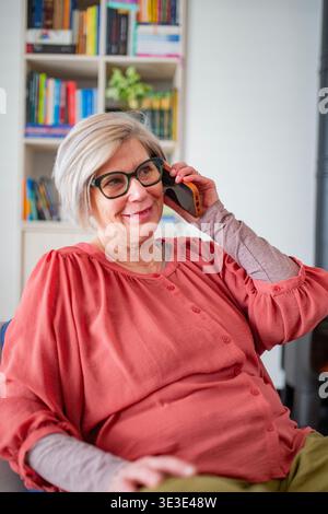 Older woman talking on phone while working from home during retirement. Stock Photo