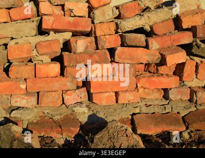 Old red brick texture. Background of a ruined red brick wall, brick wall background. Stack of old, weathered bricks. Old broken brick, close-up. Const Stock Photo