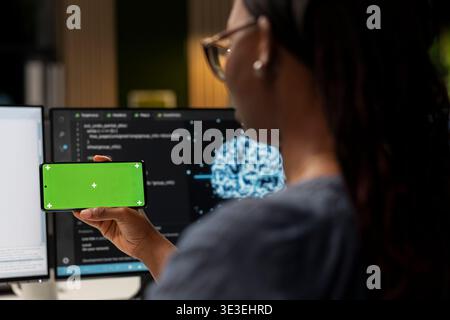 Admin using AI app on isolated screen smartphone to optimize performance and forecast issues. IT expert in tech startup office training deep learning models using mockup mobile phone Stock Photo