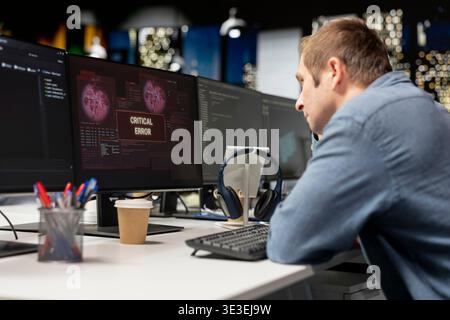 Programmer in startup office struggling to fix application errors while coding. IT professional dealing with computer bugs while coding in software development agency workplace Stock Photo