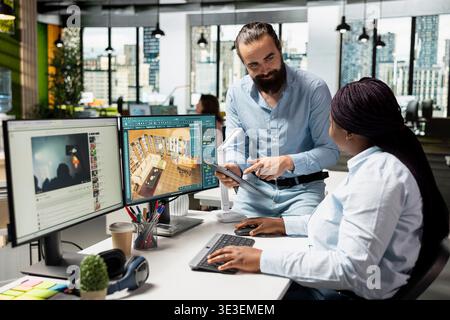 Multiethnic architects team working on interior design and layout using CAD architecture software on computer. Man and woman works with virtual assets remodeling tools to create 3D visuals. Stock Photo