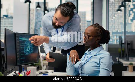 Teamworking proprietary firm colleagues using deep learning to assess stock market volatility. Brokerage company supervisor and african american woman using AI to generate investment reports Stock Photo