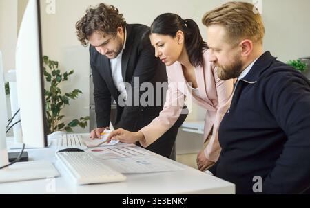 Colleagues reviewing analytics reports together at modern workplace desks Stock Photo