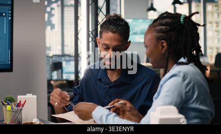 Engineers and real estate developers reviewing smart city design layout on architectural 3D models, brainstorming ideas for modern infrastructure, innovation and residential housing. Stock Photo