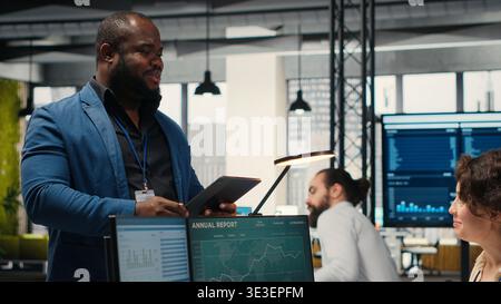 Happy colleagues sharing a high five after successful tasks accomplishment, enjoying triumph and feeling pleased with their expertise. Diverse people celebrating achievement, friendly space. Camera B. Stock Photo