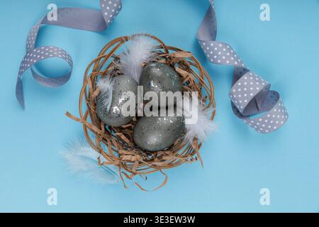 Easter eggs nest composition with ribbon on blue background Stock Photo