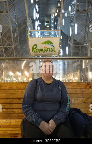 Portrait of a tourist sitting on a wooden bench inside Salina Turda salt mine, Turda, Romania. Stock Photo