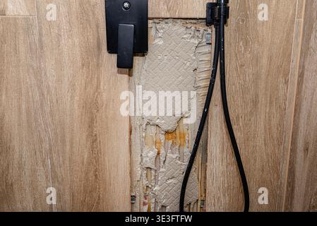 Wall damage in a shower cabin with visible water leakage and exposed tile adhesive Stock Photo