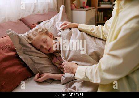 Girl Sleeping Peacefully While Adult Woman Covering with Blanket Stock Photo