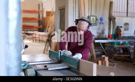 Senior craftsman working with wood planer in workshop Stock Photo