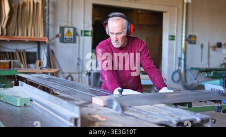 Experienced carpenter cutting wood with a panel saw Stock Photo