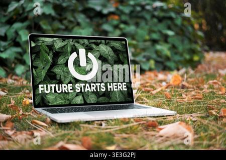 Laptop displaying power button icon and green leaves, symbolizing a fresh start for sustainability and eco-friendly technology Stock Photo