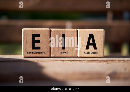 Wooden blocks in a natural outdoor setting displaying the EIA acronym for environmental impact assessment, emphasizing sustainability and ecological p Stock Photo