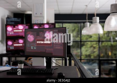 Computer displays showing hacking warning alert after security breach, cyber crime attack with error distortion message. Empty IT office having pc with system crash and malfunction. Stock Photo