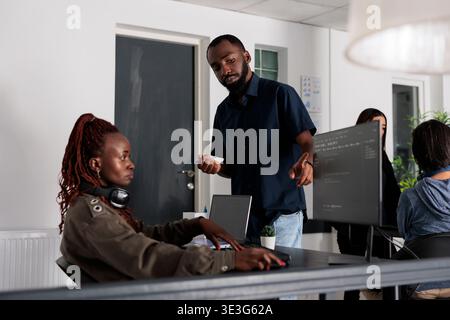African american software developers discussing about coding script in front of computer, working on server interface development. Programmers doing teamwork to plan html software language. Stock Photo