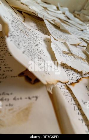 Torn, aged paper with faded ink and browned edges. Handwritten text appears smudged and uneven. Texture shows creases, tears, and yellowed tones. Ligh Stock Photo