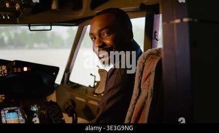 Portrait of african american copilot sitting in airplane cockpit with captain, ready to fly airline plane with control panel dashboard. Navigation command with power engine in cabin. Stock Photo