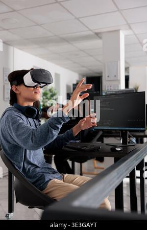 It programmer wearing virtual reality headset to code new server interface, analyzing cloud information on terminal window. Coder programming it database for internet software with vr goggles. Stock Photo
