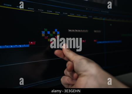 Visual editor expressing care for content creation, making heart gesture aligning with pixel art heart built from video clips on monitor screen Stock Photo
