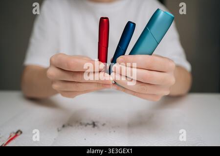 Hands holding colorful heat-not-burn electronic cigarettes after cleaning them, showing the importance of regular maintenance for device longevity and Stock Photo