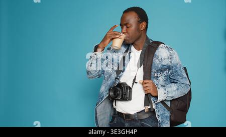 African american man with backpack working as photographer, going on vacation to take professional pictures for production. Model with camera leaving on holiday trip, capturing photos. Stock Photo