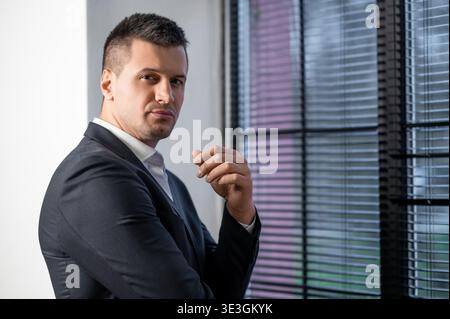 Professional man standing near window with serious look Stock Photo
