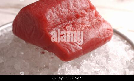 Fresh raw bluefin tuna fillet sits on a bed of crushed ice in a bowl Stock Photo