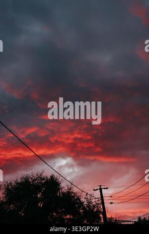 Power lines against dramatic sunset on a fall evening in October Stock Photo