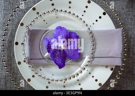 Elegant place setting with purple orchid on plate. Stock Photo