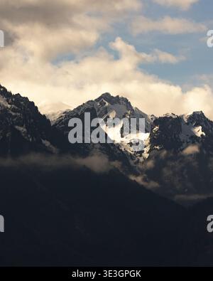Dramatic clouds partially obscure sun-kissed peaks in the French Alps Stock Photo