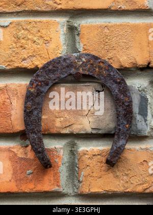 Vertical shot of a rusty old horseshoe on a red brick wall as a Stock Photo