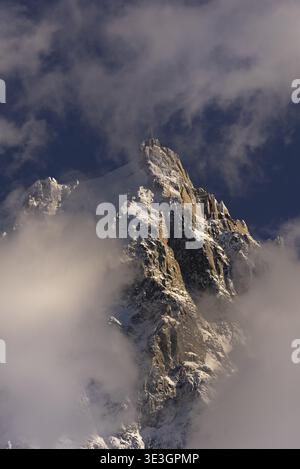 Dramatic clouds swirling around the sunlit peak of Aiguille du Midi Stock Photo