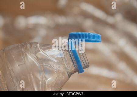 Water bottle cap is off and resting on top of an empty plastic bottle near crumpled plastic Stock Photo