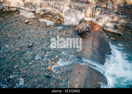 River flowing over small weir with colorful pebbles in clear water Stock Photo