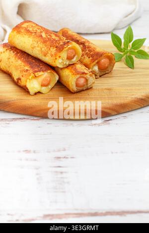 Delicious homemade fried or baked rolls made of wheat bread, sausage and cheese. Gourmet breakfast, brunch. Served on a wooden board with basil. White Stock Photo
