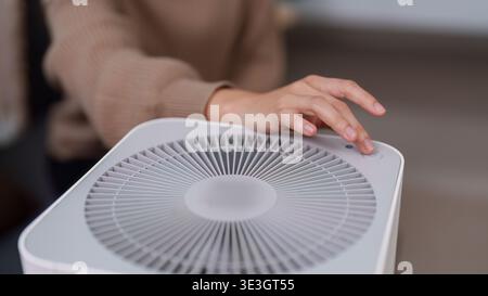 Hand adjusting settings on a modern air purifier Stock Photo