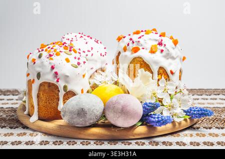 A festive Easter table setting featuring decorated kulich cakes, colorful eggs, and blooming flowers on a traditional embroidered cloth Stock Photo