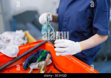 worker hand holding long neck oil lubricant lube oil drop at machine part in heavy industry workshop Stock Photo
