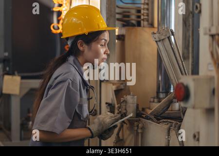 Professional Engineer female worker work monitor check the operation of the machinery in heavy industry metal factory Stock Photo