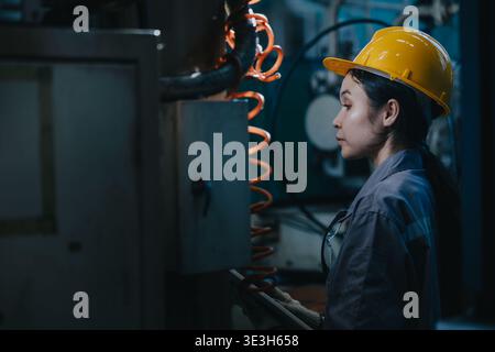 Engineer Asian woman working in heavy industry factory service maintenance machine in dark late night for night shift worker Stock Photo