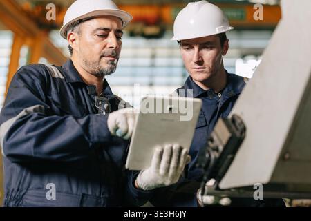 Senior engineer team work with young worker help together checking control operate machine with tablet computer technology Stock Photo