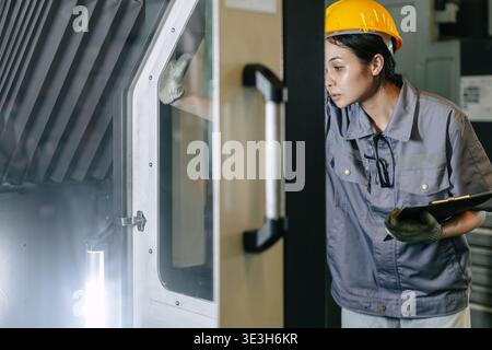 Professional young Asian Engineer woman working control operate CNC machine in heavy industry factory happy smiling good welfare Stock Photo