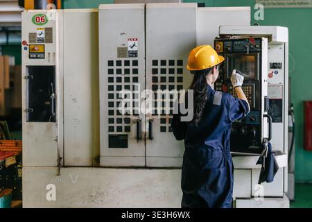 Professional young Asian Engineer woman working control operate CNC machine in heavy industry factory happy smiling good welfare Stock Photo