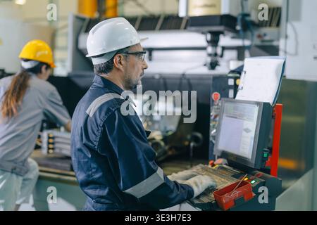 CNC Lathe Machine Engineer Operator Worker Working Entering Work Batch Production Program Data at Heavy Metal Factory Stock Photo