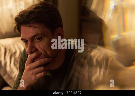 Portrait of Young Man Sitting Indoors Looking Thoughtful Stock Photo