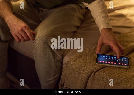 Young Man Using Smartphone to Control Smart Home Lighting Stock Photo