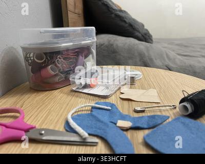 A tailor's sewing kit on a table. Needles, thread, and fabric for sewing. Stock Photo