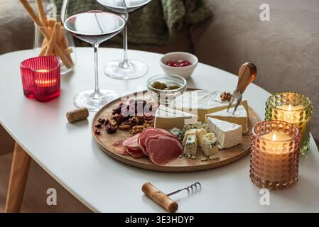 Elegant charcuterie board composition featuring assorted cheeses, cured meats, walnuts, dried cranberries, breadsticks, olives, and red jelly, paired Stock Photo