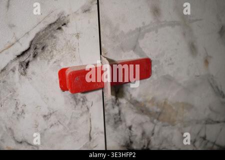 A Close-Up View of a Unique Red Handle on a Sealed Marble Cabinet Door with Natural Patterns Stock Photo